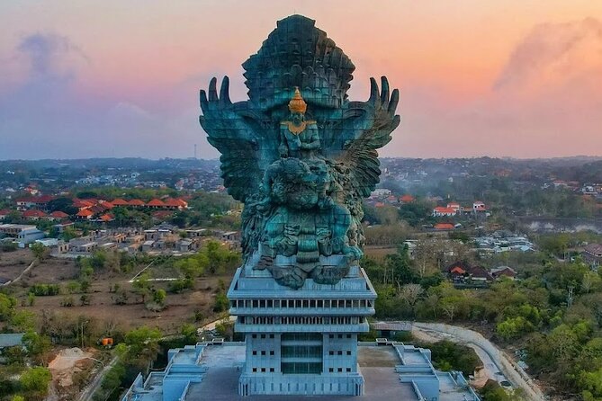 Garuda Wisnu Kencana lit against a dusk sky above its stone plaza
