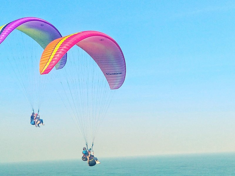 Tandem paragliders over the cliffs and surf on Bali's southern coast