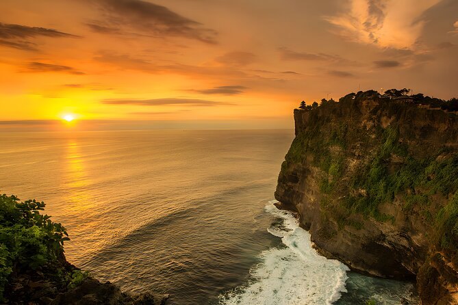The sun on the horizon from the Bukit, a dark headland at the right
